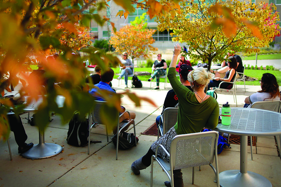 A class is held outside amidst fall leaves.