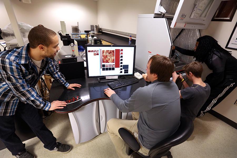 A group of students work around a computer.